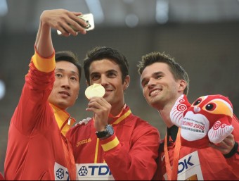 López, amb la medalla d'or, fotografiat pel xinès Wang i el canadenc Thorne dalt del podi de 20 km marxa AFP