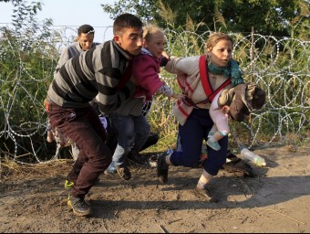 Diversos refugiats, dos d'ells menors, travessen la frontera de filferro per entrar a Hongria REUTERS