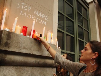 Una noia col·loca una espelma davant d'una pintada on es llegeix Stop Mare Mortum ACN