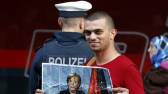 Un refugiat a l'estació de tren de Munic amb un retrat de Merkel REUTERS