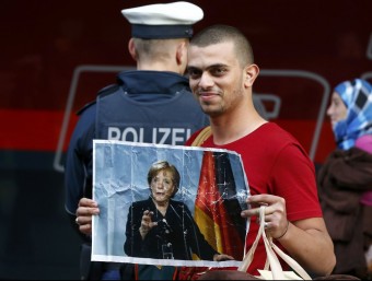 Un refugiat a l'estació de tren de Munic amb un retrat de Merkel REUTERS