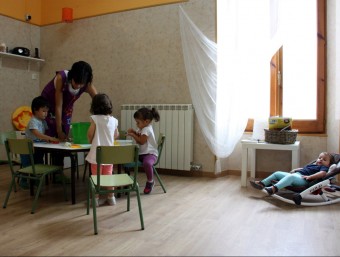 L'educadora de la llar d'infants rural de les Pallargues fent una activitat amb els nens, i a la dreta una dels petits descansant en un bressol ORIOL BOSCH / ACN
