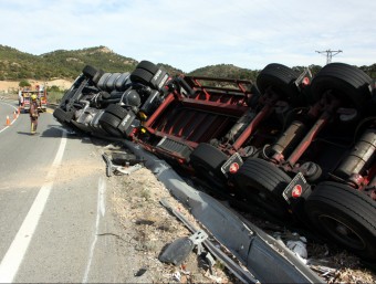 El camió accidentat a la cuneta de la carretera N-420 mentre agents dels Mossos d'Esquadra controlen el trànsit. Imatge del 18 de setembre. Pla general del camió tombat ACN