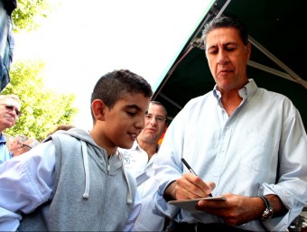 Xavier García Albiol signa un autògraf a Ahmed, un nen d'origen àrab que li ha demanat la firma fins a tres cops mentre el candidat passejava pel mercat de Cerdanyola, a Mataró ACN