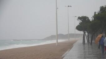 Una parella camina amb dificultats pel passeig marítim de Platja d'Aro a causa del vent i la pluja ACN