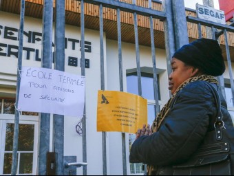 Un soldat a la Gran Place de Brussel·les, i una dona llegint el cartell d'una escola tancada per seguretat, ahir reuters
