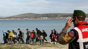 Un gendarme turc observa un grup de refugiats a la localitat de Cesme, davant l'illa grega de Quios REUTERS