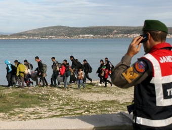 Un gendarme turc observa un grup de refugiats a la localitat de Cesme, davant l'illa grega de Quios REUTERS