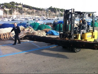 Amb una grua transportant ahir al matí la part de la nau que van treure de les xarxes al port d'Arenys. E. FERRAN