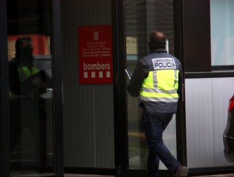 Pla persona d'un policia nacional entrant amb armilla reflectora al Parc de Bombers de Sant Boi de Llobregat, amb el cartell de Bombers a l'entrada, el 13 de gener del 2016 ACN