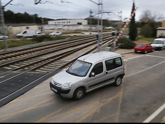 El pas a nivell del tren a Flaçà, amb un cotxe passant quan baixa la barrera MANEL LLADÓ