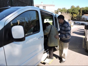 Un home ajuda una dona gran a pujar en un taxi del municipi en el programa de taxis subvencionats AJUNTAMENT ALELLA