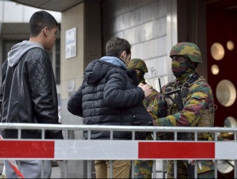 Soldats de l'exèrcit belga escorcollen uns ciutadans a l'entrada d'una estació de metro de Brussel·les
