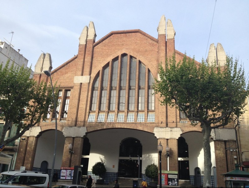 La façana monumental del mercat està situat en plena riera, a pocs metres de l'església E. FERRAN