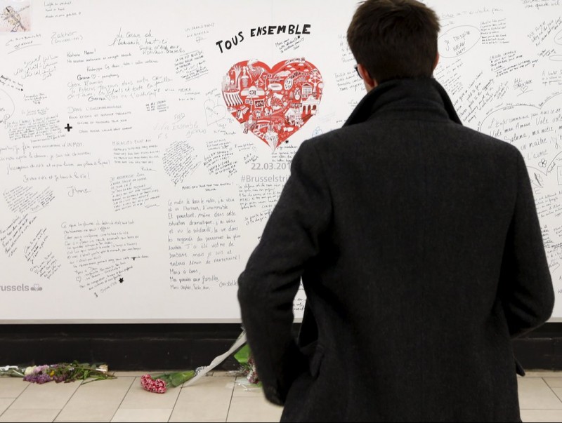 Un passatger observa el mural en homenatge a les víctimes dels atemptats, aquest dilluns a l'estació de metro Maelbeek de Brussel·les REUTERS