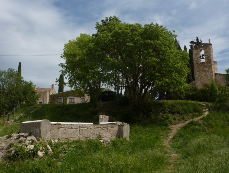 L'estructura del rentador, molt deteriorada , i al fons, l'església de Santa Maria de Porqueres. R. E