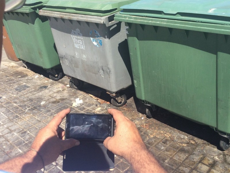 Un ciutadà fa una foto amb el seu mòbil a uns contenidors de recollida de brossa R.M.B