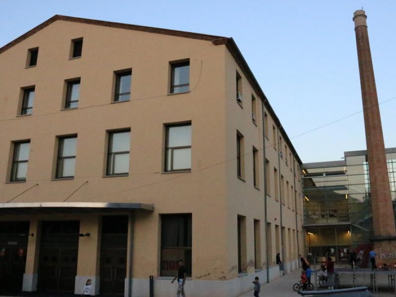 Façana de Cal Gallifa. Al mòdul transparent, de nova construcció, hi ha l'accés a la biblioteca; davant, la xemeneia de la fàbrica N. BADRENAS